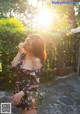 A woman in a floral dress standing in a garden.