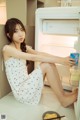 A woman sitting on the floor in front of an open refrigerator.