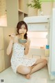 A woman sitting on the floor eating a bowl of noodles.