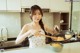 A woman in a kitchen preparing food with chopsticks.