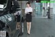 A woman standing next to a black car in a garage.