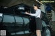 A woman writing on a clipboard next to a car.