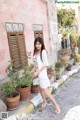 A woman in a white dress is walking down the street.