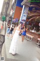 A woman in a white dress standing in front of a bar.