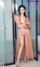 a woman in a pink robe standing in front of a glass door