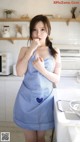 A woman in a blue apron standing in a kitchen.