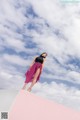 A woman standing on top of a pink and white building.