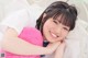 A young girl laying on a bed holding a pink teddy bear.