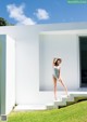 A woman in a bathing suit standing on the steps of a house.