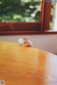 A person holding a ping pong ball on a wooden table.