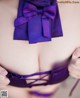 A close up of a woman wearing a purple bra with a purple bow.