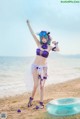 A woman in a purple bikini standing on a beach.