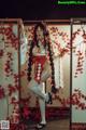 A woman in a red and white kimono posing for a picture.