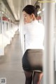 A woman in a white shirt and black skirt posing for a picture.