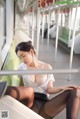 A woman in stockings and a white shirt is sitting on a train.