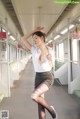 A woman in a white shirt and black skirt on a train.