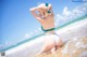 A woman in a bikini sitting in the ocean.