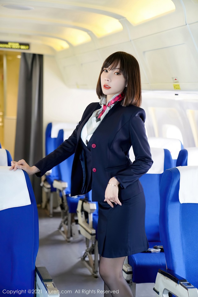 A woman in a business suit standing in an airplane.