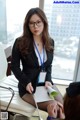 A woman in a business suit sitting on a chair.