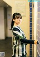 A young woman leaning against a wall in a hallway.