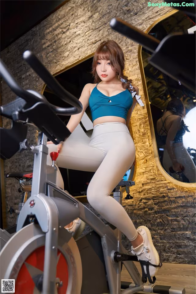 A woman sitting on a stationary bike in a gym.