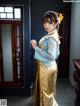 A woman in a blue and gold dress standing in front of a door.