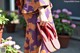 A woman in a purple kimono holding a pair of red flip flops.