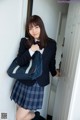 A young woman in a school uniform leaning against a door.