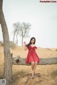 A woman in a red dress sitting on a tree branch.