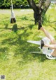 A woman laying on a white chair under a tree.