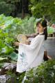 A woman in a white dress holding a fan in a garden.