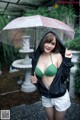 A woman in a green bikini holding an umbrella.