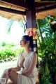 A woman in a white dress sitting on a wooden pole.