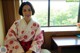 A woman in a kimono sitting in front of a window.