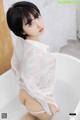 A woman in a white shirt is sitting in a bathtub.