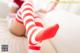 A woman in red and white striped stockings laying on a bed.