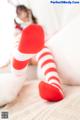 A little girl in red and white striped stockings laying on a bed.