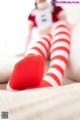 A woman in red and white striped stockings sitting on a bed.