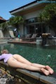 A woman laying on the edge of a swimming pool.