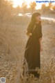 A woman in a black dress standing in a field.