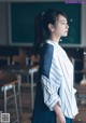 A woman standing in front of a blackboard in a classroom.