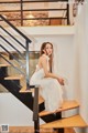 A woman in a white dress sitting on a wooden staircase.