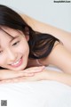 A woman laying on a bed smiling at the camera.