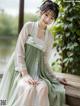 a woman in a green and white dress sitting on a bench