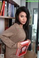 A woman sitting on a table holding a book.