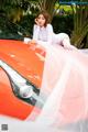 A woman sitting on top of an orange car.