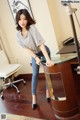 A woman leaning on a desk in a room.