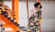 A woman in a kimono standing next to a set of stairs.