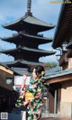 A woman in a kimono standing in front of a pagoda.