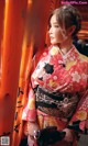 A woman in a kimono standing in front of a torii gate.